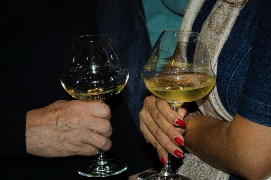 Deux invités trinquent, verres de vin blanc à la main
