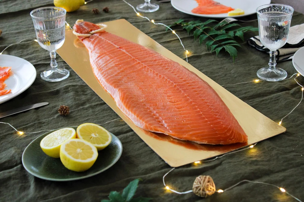 Filet entier de saumon fumé sur une table de fête, citrons et guirlande lumineuse
