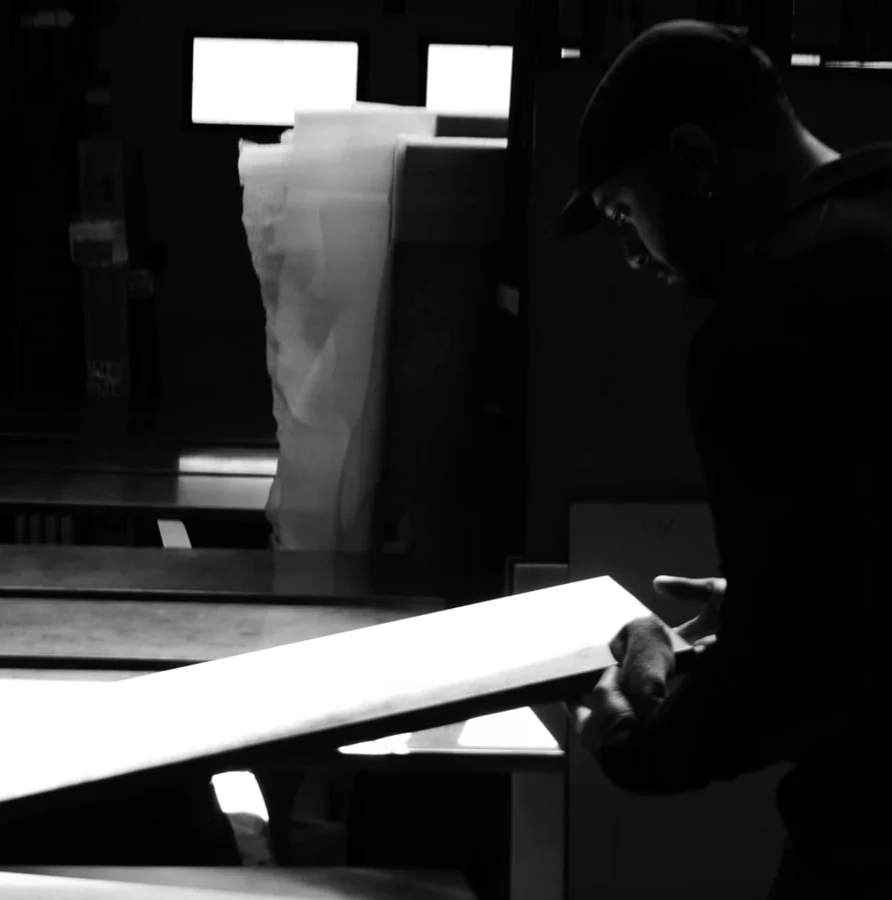 L’architecte de Prémices penché sur une plaque de métal dans son atelier, en noir et blanc