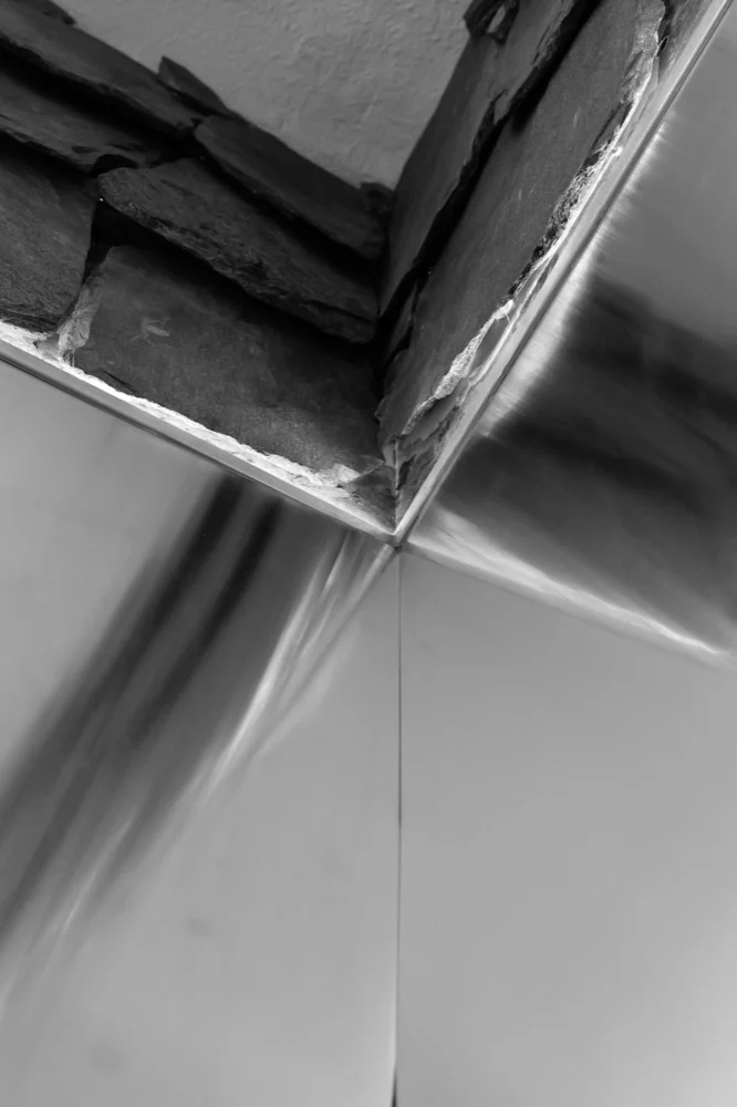 Angle en inox brossé sous un mur de pierre
